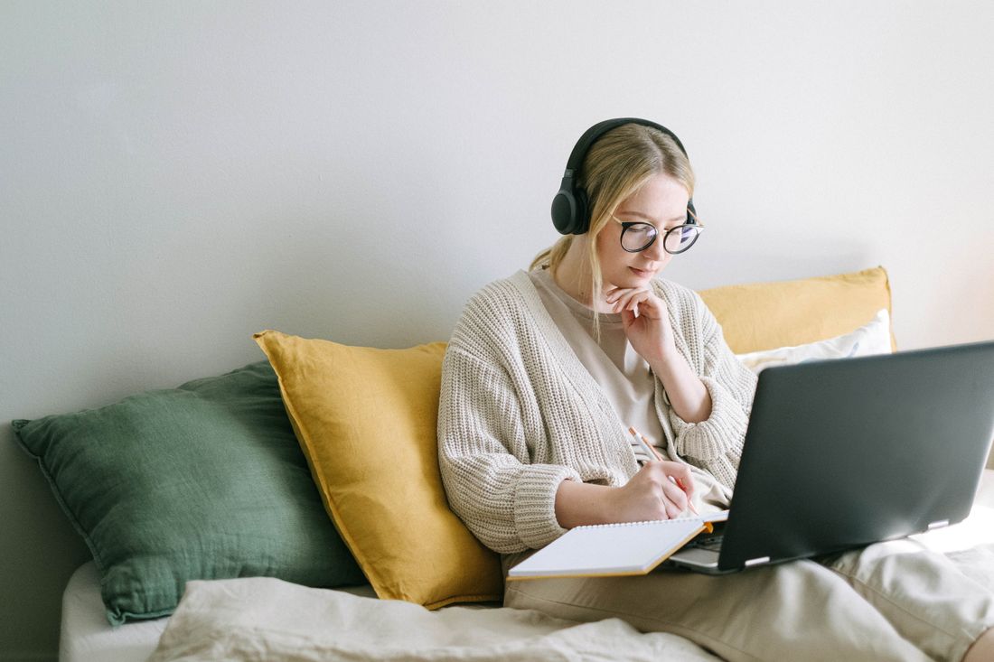 A woman with headphones working at a laptop